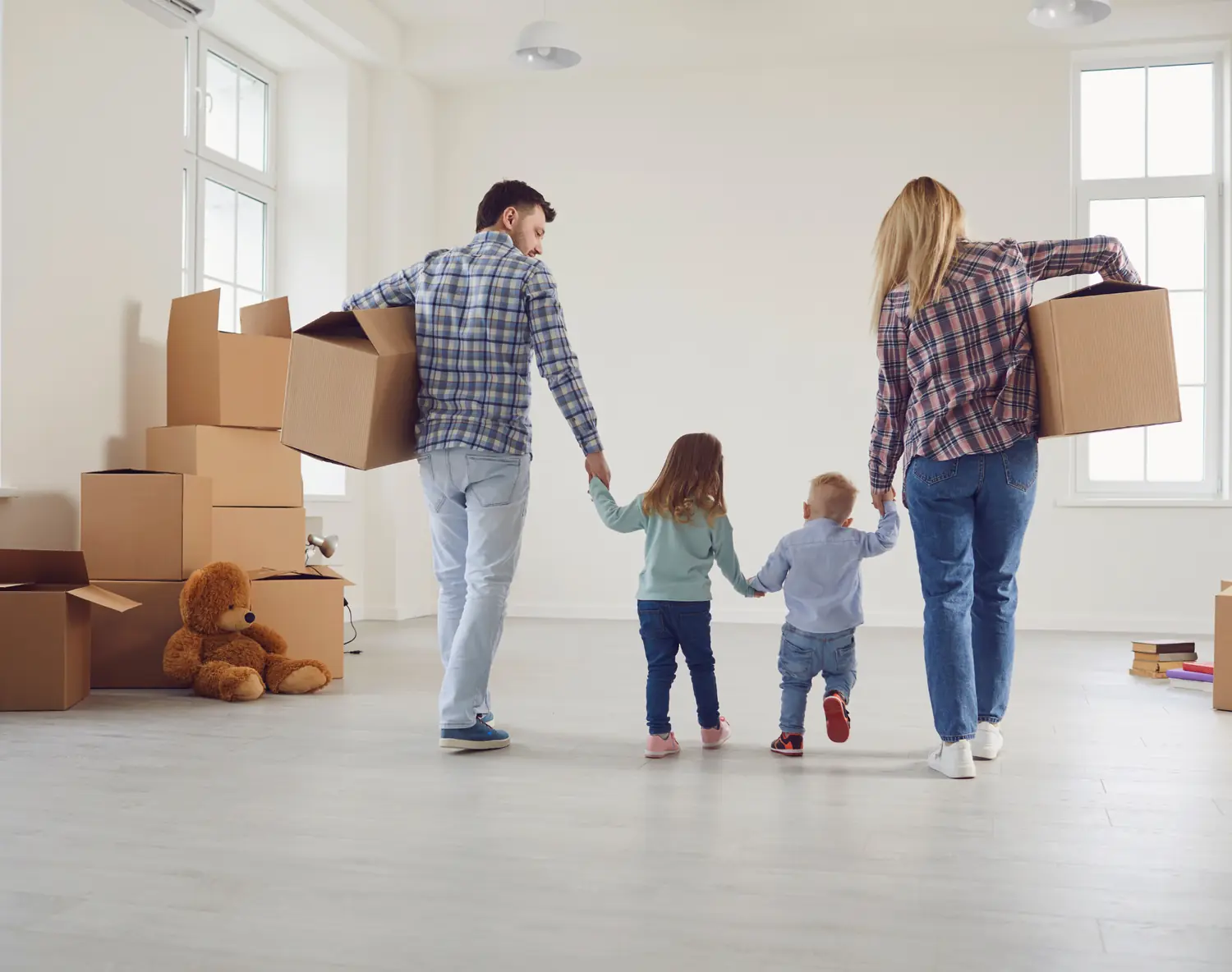 Família a entrar na sua nova casa, com caixas de mudança